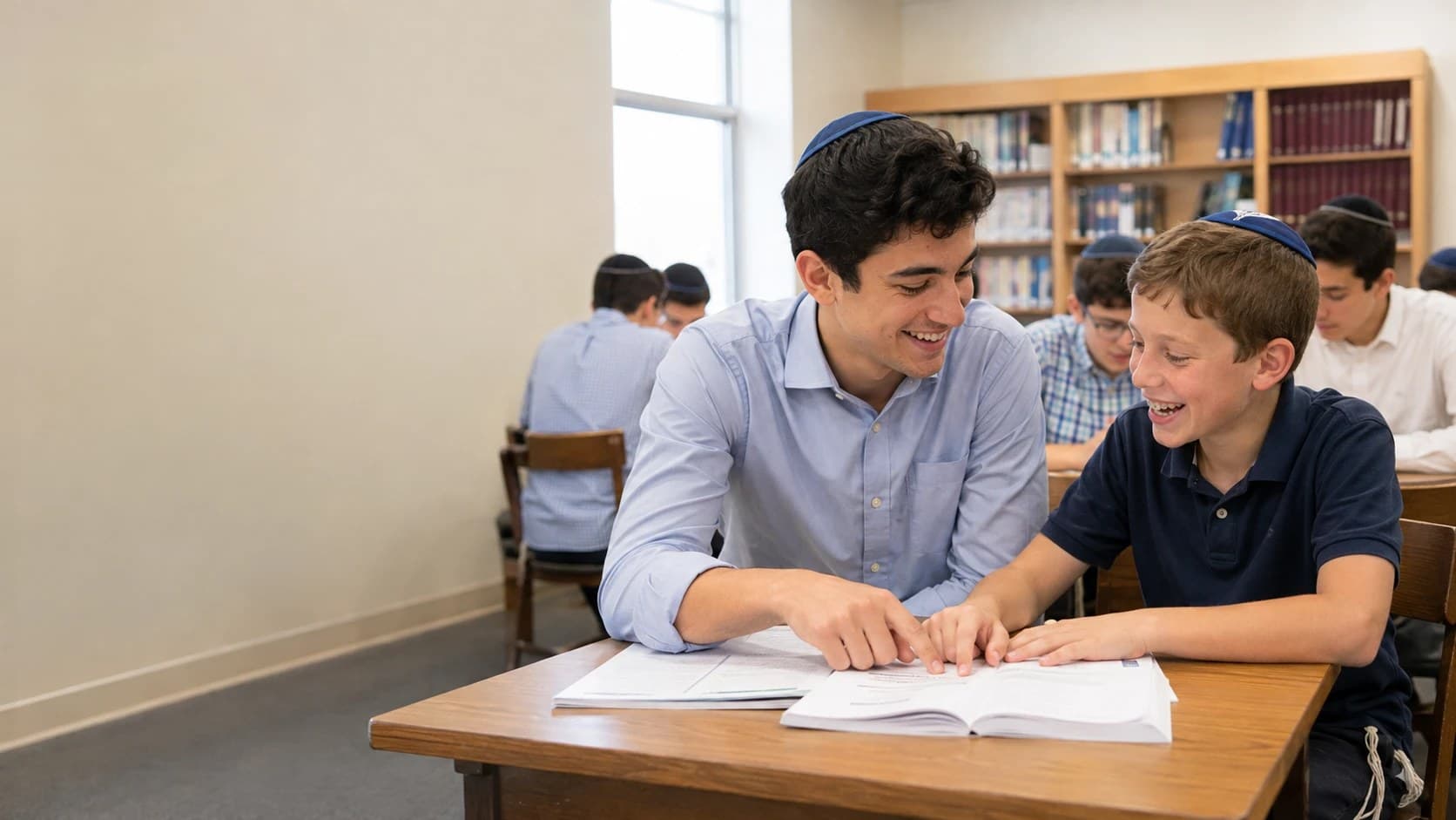 An older student tutoring a younger student at a library table